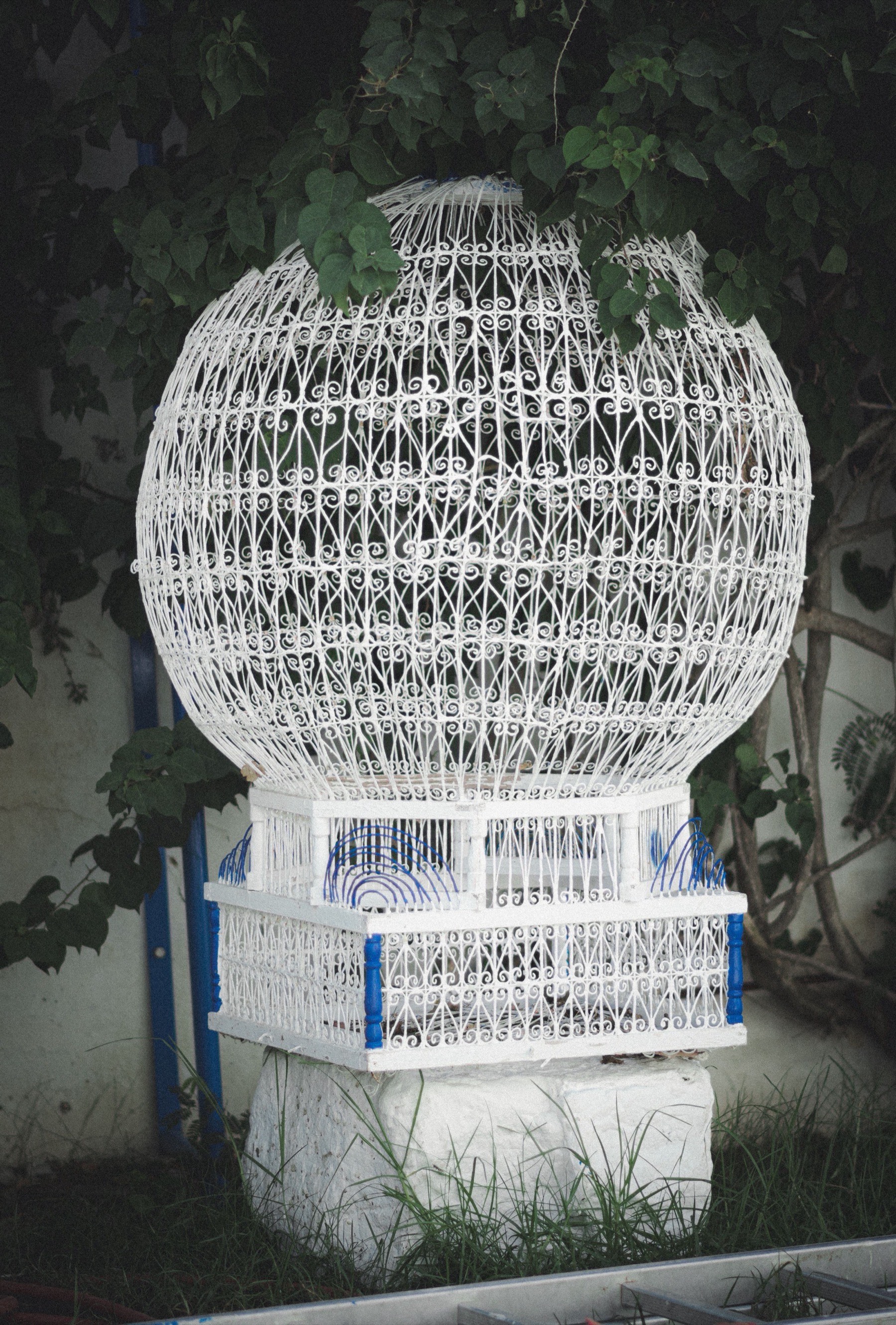 An ornate hand-worked white wire birdcage, a traditional Tunisian courtyard fixture