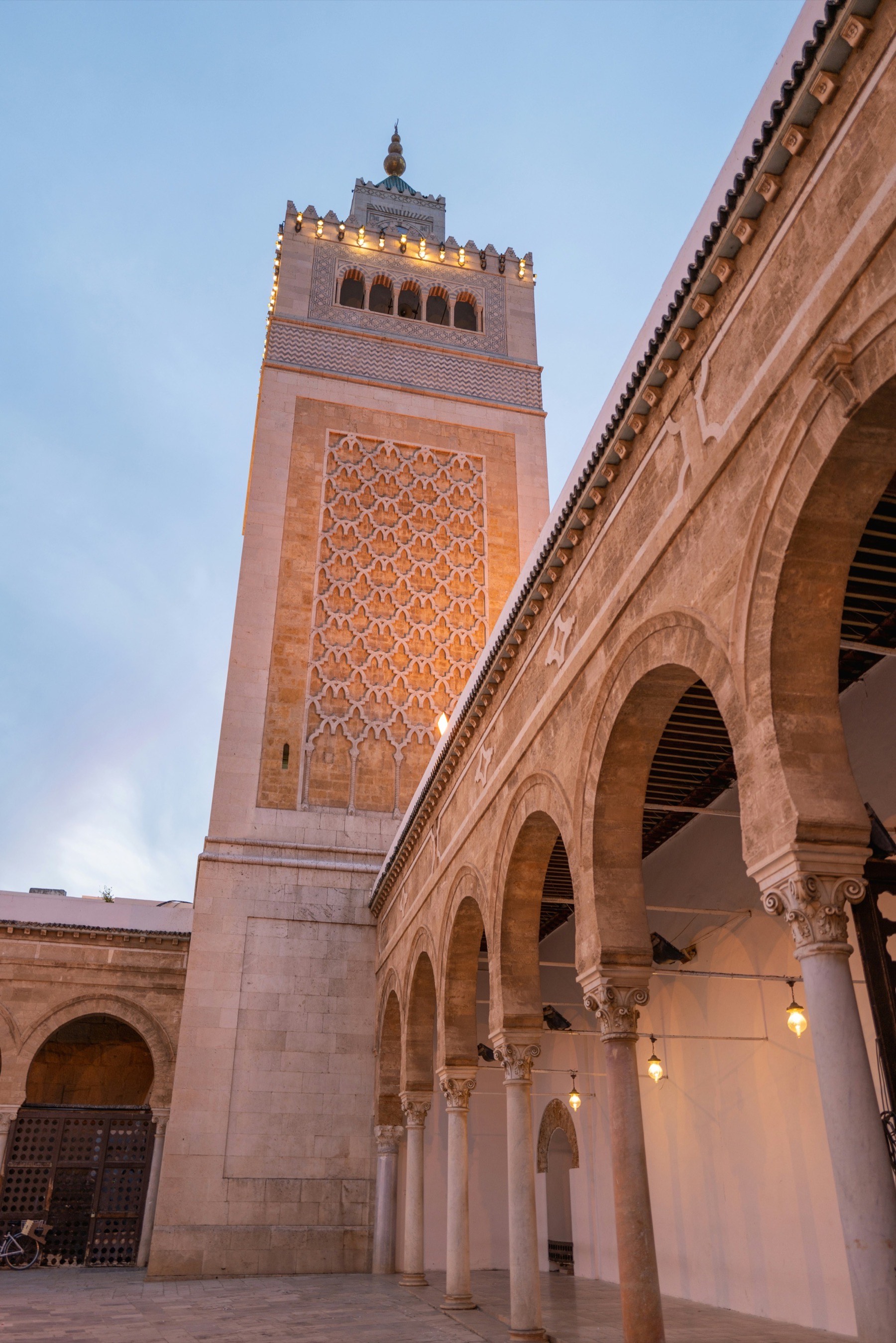 The minaret and stone colonnade of the Great Mosque of Kairouan at golden hour